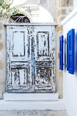 an old door on the side of a building with blue shutters at seasalthouse - famous tv location in Koskinou