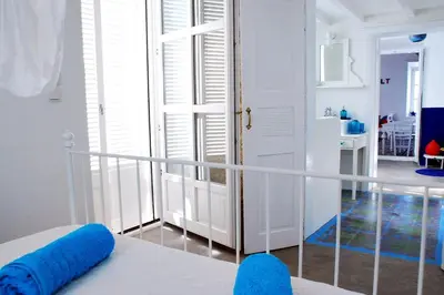 a room with a balcony with a bed with blue pillows at seasalthouse - famous tv location in Koskinou