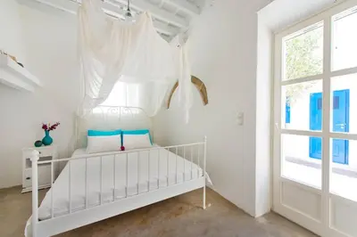 a white bedroom with a white bed and a window at seasalthouse - famous tv location in Koskinou