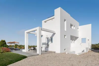 a white house with a patio and grass at Villa Katerina - Soroni in Rhodes Town