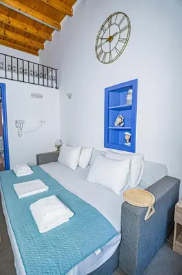 a bedroom with a bed with a clock on the wall at Kali Strata 2 - Downtown in Symi