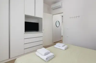 a white room with white cabinets and a tv at Aegean Retreat Luxury Apartment in Rhodes Town