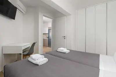 a white bedroom with two beds and a desk at Aegean Retreat Luxury Apartment in Rhodes Town