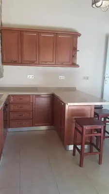 a kitchen with wooden cabinets and a table and stool at Villa Pavlos in Symi
