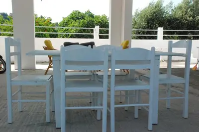 a dog laying on a table and chairs on a porch at Nadia's House 1 in Afantou