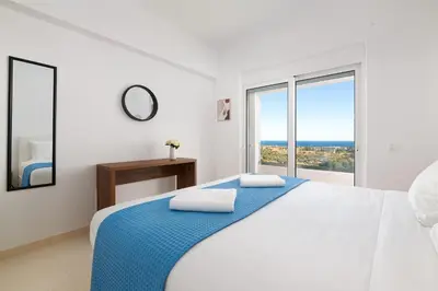 a white bedroom with a bed and a large window at Villa Zoe Blu in Kalathos