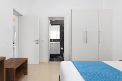 a white bedroom with a bed and a bathroom at Villa Zoe Blu in Kalathos