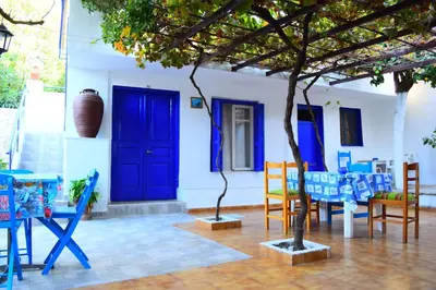 a house with blue doors and chairs and a tree at Stathis in Rhodes Town