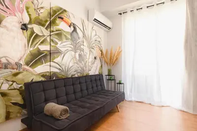 a living room with a black couch in front of a mural at Mandraki City Center Apartments in Rhodes Town