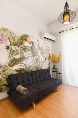 a black couch in a room with a mural of birds at Mandraki City Center Apartments in Rhodes Town