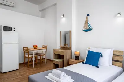 a bedroom with a bed and a kitchen with a table at Stegnale Studios in Archangelos