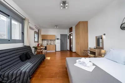 a bedroom with a large bed and a kitchen at Stegnale Studios in Archangelos