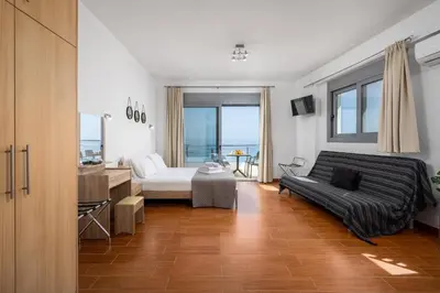 a bedroom with a bed and a desk and a couch at Stegnale Studios in Archangelos