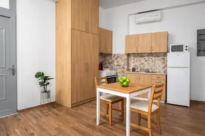 a kitchen with a table and chairs and a white refrigerator at Stegnale Studios in Archangelos
