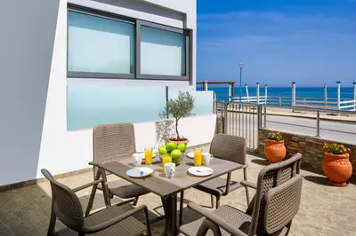 a table and chairs on a patio with the beach at Stegnale Studios in Archangelos