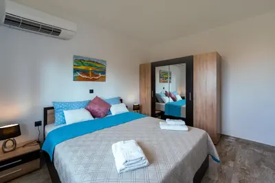 a bedroom with a bed with blue and white sheets at Sweet Home Luxury Apartments in Ialyssos