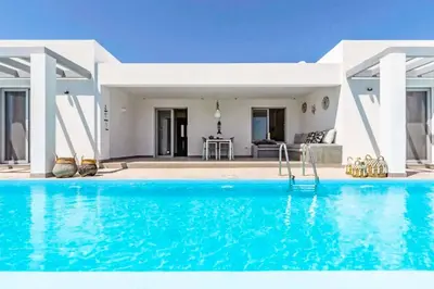 a villa with a swimming pool in front of a house at Villa Anthos Kerasia in Gennadi