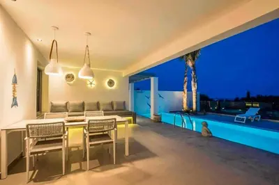 a living room with a table and chairs and a view at Villa Anthos Kerasia in Gennadi