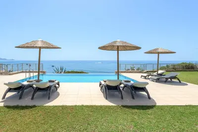 a group of chairs and umbrellas next to a pool at Paradise Beach II in Kiotari