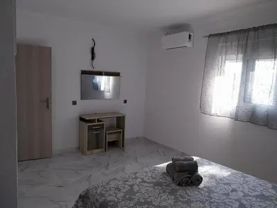 a white room with a bed and a television at Paradis Studios in Archangelos