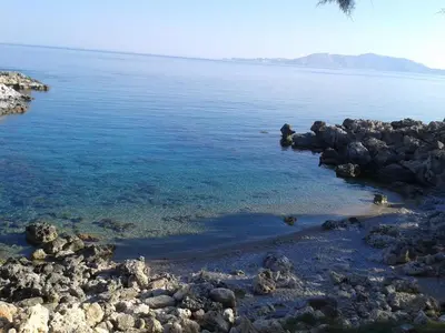 a group of rocks on the shore of the water at Paradis Studios in Archangelos