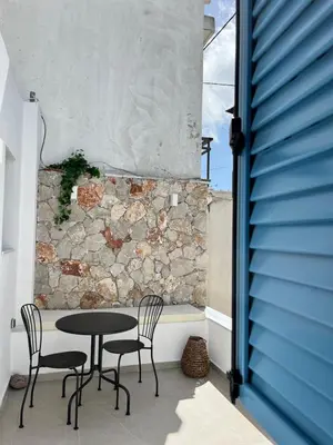 a table and chairs on a patio with a stone wall at Casa Stergia - Village Project in Psinthos