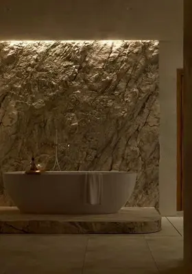 a bath tub in a bathroom with a stone wall at Elaia Luxury House in Archangelos