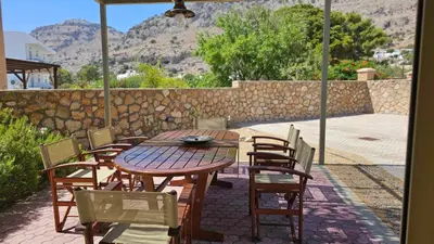a wooden table and chairs on a patio at Villa Libre Mare, your cozy vacation villa in Pefki Rhodes