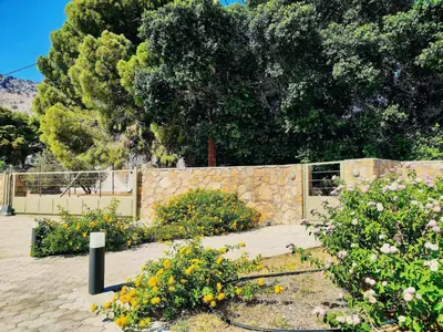 a garden with flowers in front of a stone fence at Villa Libre Mare, your cozy vacation villa in Pefki Rhodes