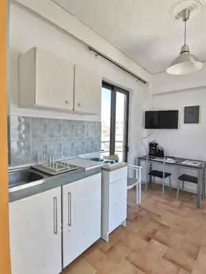 a kitchen with white cabinets and a sink and a desk at 3rd floor apartment in town with sea view in Rhodes Town