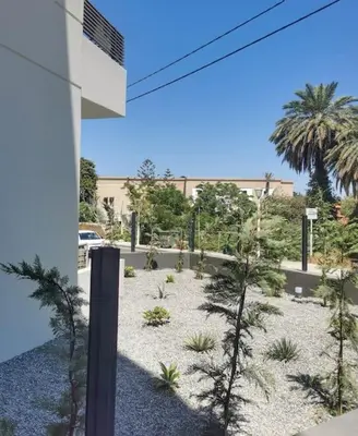a view of a garden with palm trees and a building at Uni cozy city apartment in Rhodes Town