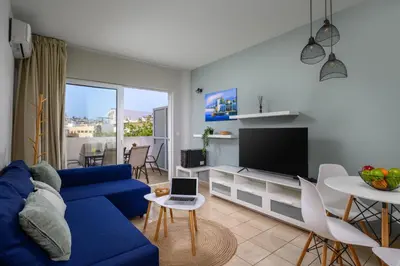 a living room with a blue couch and a tv at Elli Beach Downtown Apartments in Rhodes Town