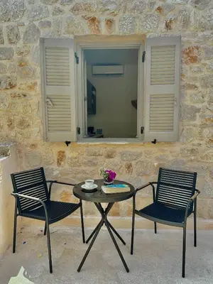 two chairs and a table in front of a stone wall at Serenity Suites in Halki