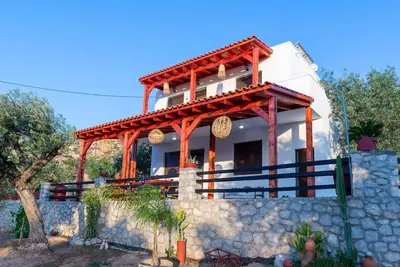 a house with a stone wall in front of it at Blue Bay Villas , First Floor in Archangelos