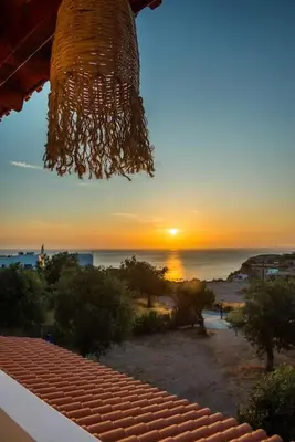 a chandelier hanging from a building with the sunset in the background at Blue Bay Villas , First Floor in Archangelos