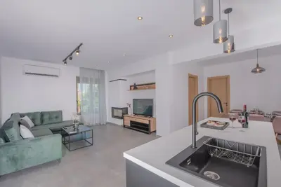 a kitchen and living room with a sink and a couch at Anthemis modern & spacious in Koskinou