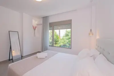 a white bedroom with a large white bed and a window at Anthemis modern & spacious in Koskinou
