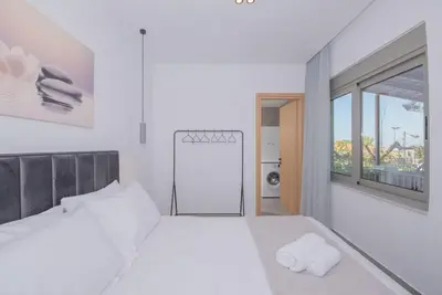 a white bedroom with a large bed and a window at Anthemis modern & spacious in Koskinou