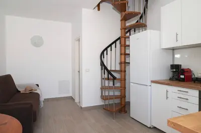 a kitchen with a spiral staircase next to a white refrigerator at Oceanis apartment in Symi