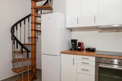 a kitchen with a white refrigerator and a spiral staircase at Oceanis apartment in Symi
