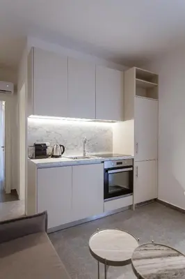 a kitchen with white cabinets and a sink and a table at Luxury Apartments Of Colossus in Rhodes Town