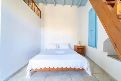 a white bedroom with a bed and a staircase at Afaia Apartments in Symi