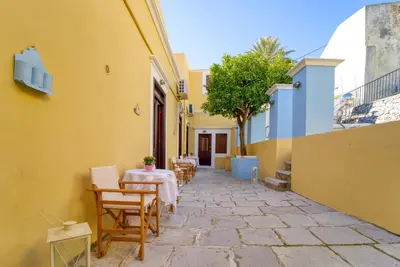 a patio with a table and chairs in a building at Afaia Apartments in Symi