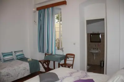 a bedroom with two beds and a table and a sink at Medieval Rose Guest House in Rhodes Town