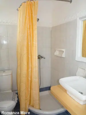 a bathroom with an orange shower curtain next to a toilet at Romantza Mare in Kallithea Rhodes