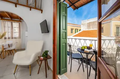 a room with a balcony with a table and chairs at Lito Studio in Symi