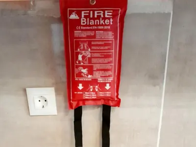 a fire blanket sign on a wall next to a lightswitch at 