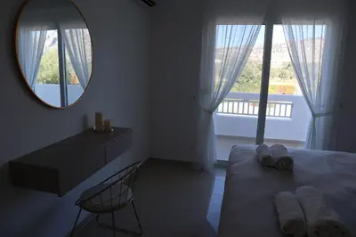 a bedroom with a bed with a mirror and a chair at Grande View Haraki in Haraki