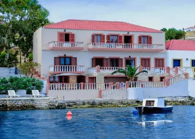 a house on a river with a boat in the water at Waterfront Family Villa in Halki
