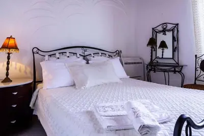a bedroom with a white bed with two lamps and a mirror at Waterfront Family Villa in Halki